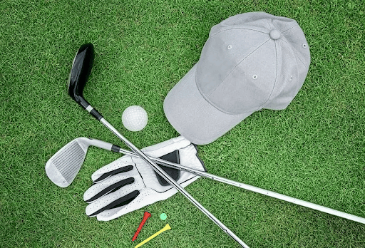 Golf irons, ball, glove and cap laid out on grass before a static club fitting session